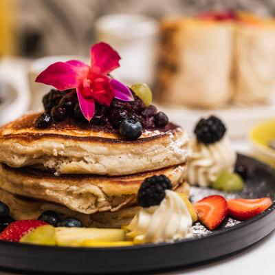 Stacked pancakes with mixed berry compote, seasonal fruit, and mascarpone cheese.
