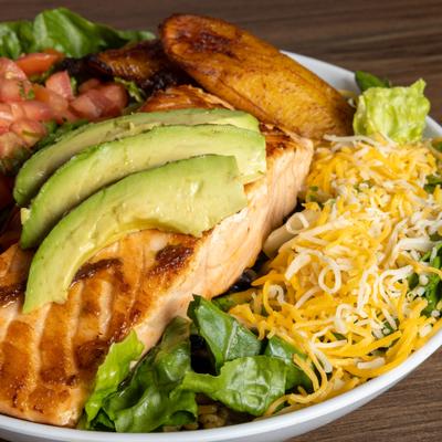 Salmon Bowl with sliced avocado, shredded cheese, tomato salsa, and plantain slices.