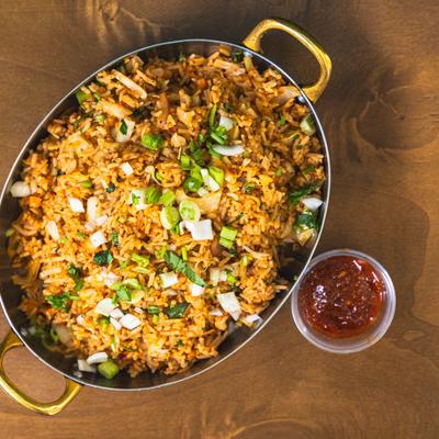 Schezwan fried rice with vegetables and sauce on the side.