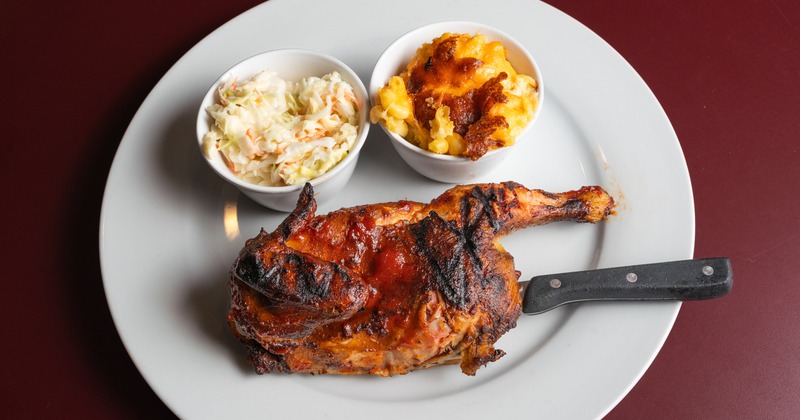 Half BBQ Chicken, coleslaw, and mac and cheese on a white plate