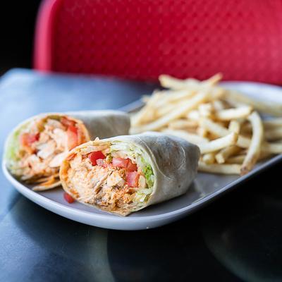 Chicken wrap with lettuce, tomatoes, and fries.