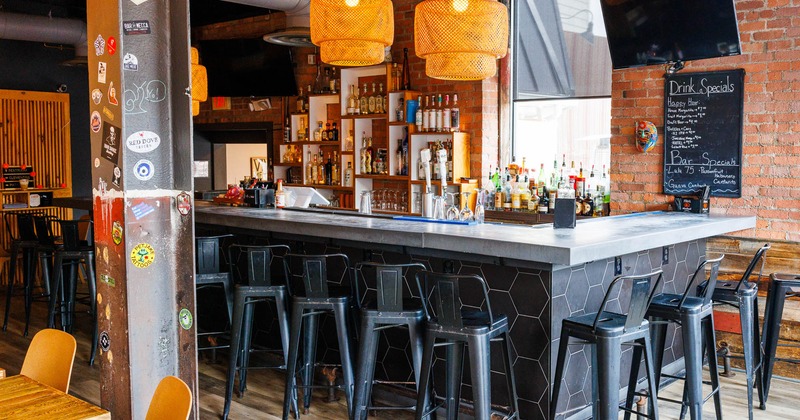 Interior, bar area, marble top bar with metal stools, drink shelves in the back, brick walls