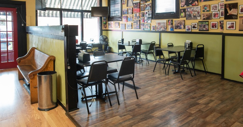 Casual dining interior with a red door, wooden bench, and black tables and chairs