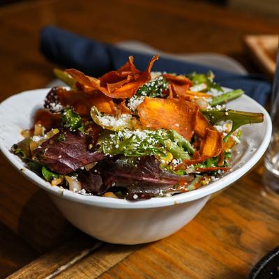 Mixed greens salad topped with sweet potato chips and cheese crumbles.