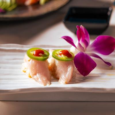Yellowtail Sushi topped with jalapeno slices and sauce.