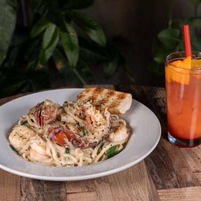 Lobster and Shrimp Cajun Alfredo served on a table with a cocktail.
