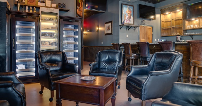 Interior, black leather armchairs, bar area in the back