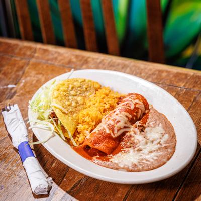 Combo plate featuring a enchilada, crispy taco and sides of rice and beans.