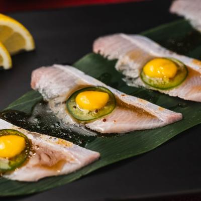 Yellowtail sashimi topped with a slice of jalapeño and a citrus-soy glaze.
