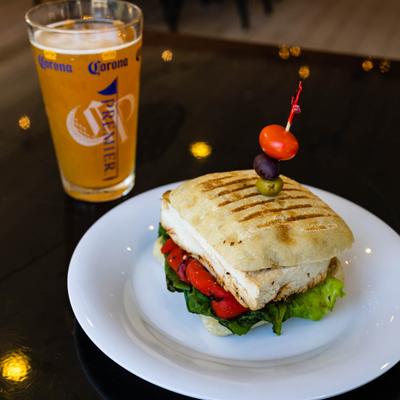 Chicken Pesto Panini Sandwich served with a glass of beer