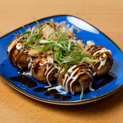 Takoyaki drizzled with a sauce and sprinkled with bonito flakes.