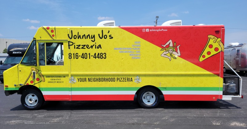 Colorful pizza truck with red, yellow, and green design parked on a parking lot