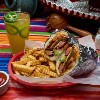 Foil-wrapped torta sandwich accompanied by crinkle-cut fries and a jalapeno margarita.