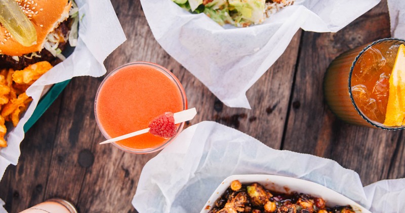 A top view of assorted food and drinks on a wooden table