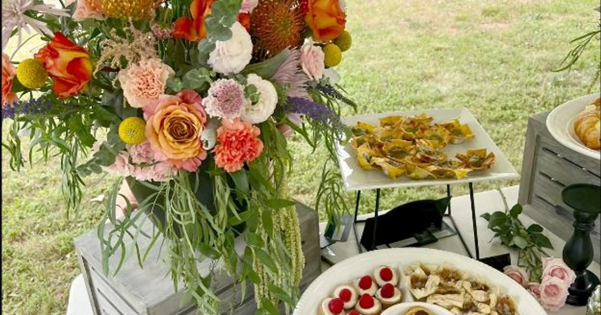 Outdoor catering display featuring a colorful floral arrangement and various appetizers