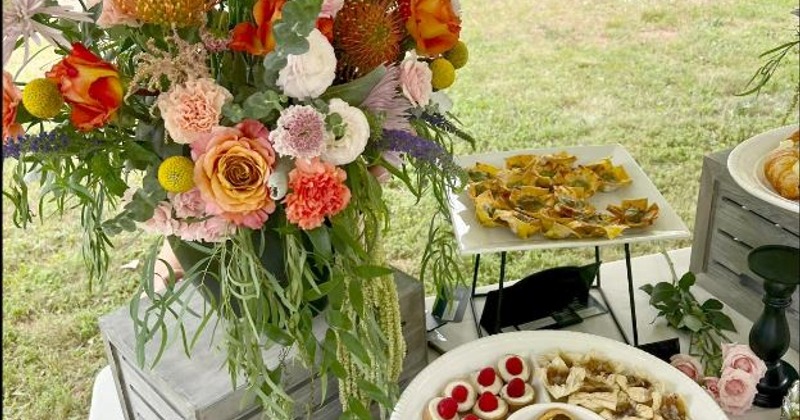 Outdoor catering display featuring a colorful floral arrangement and various appetizers