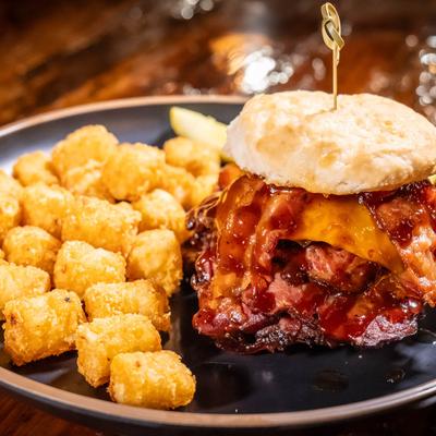Brisket sandwich on biscuit served with tater tots.