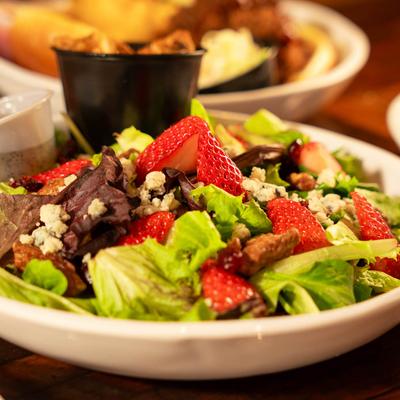 Strawberry Patch Salad with Oven Roasted Chicken displayed with other food dishes, close up.