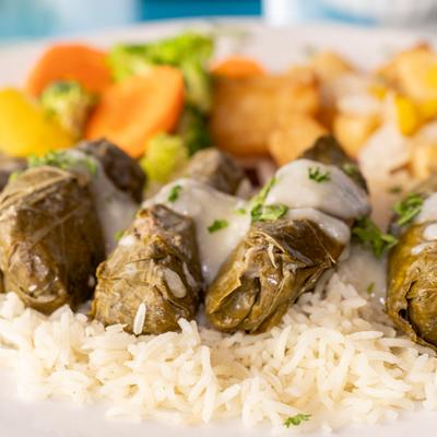 Beef and rice stuffed grape leaves served over rice with steamed vegetables.