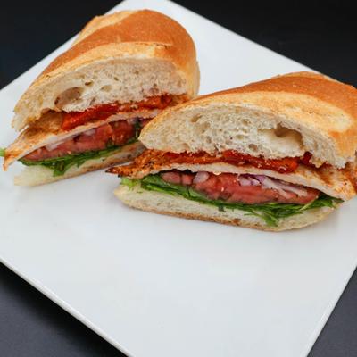 Grilled chicken sandwich with arugula, onions, tomatoes, and roasted peppers.