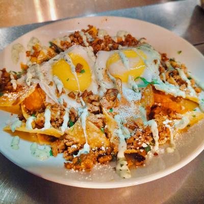 Tortilla chips sauteed with red sauce, with fried eggs, chorizo, cilantro, cotija, and sour cream.