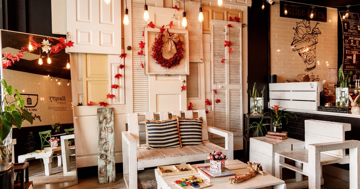 Rustic coffee shop interior with white wooden furniture, red leaf decorations, and warm lighting