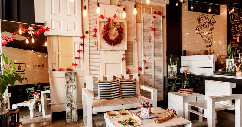Rustic coffee shop interior with white wooden furniture, red leaf decorations, and warm lighting