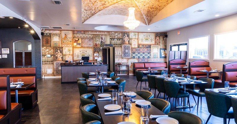 Interior with green chairs, red cushioned booths and a tiled wall with artwork