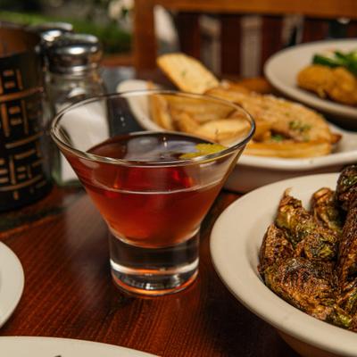 Cocktail served in a martini glass, alongside a plate of Brussels Sprouts.