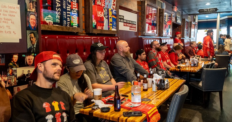 Interior, bar area, guests enjoying drinks and a soccer match broadcast