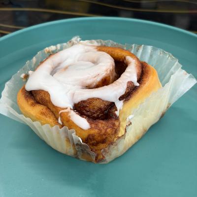Iced cinnamon roll on a blue plate.