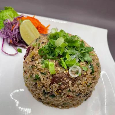 Egg fried rice with a lime wedge and a small salad on the plate.