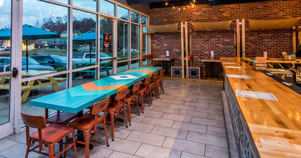 Interior, long table setup for thirteen, large shop window, seating booths, red brick wall