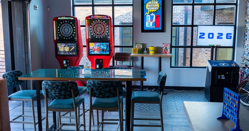 A glass-top table with chairs, a recreational area with electronic dartboards