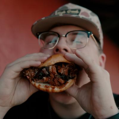 Person eating a sandwith with pulled pork.