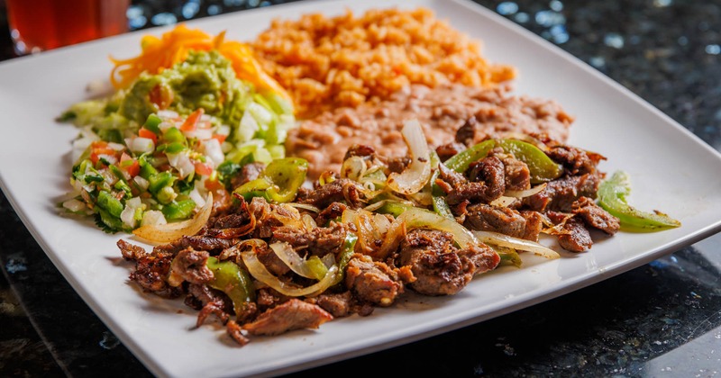 Beef fajitas served with rice, refried beans, lettuce, pico de gallo, guacamole