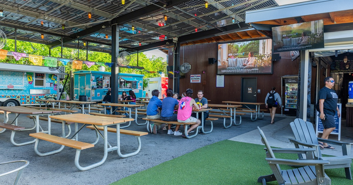 Covered patio seating area with conjoined wooden tables and benches