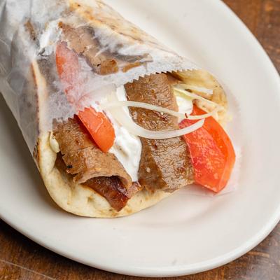 A white plate with gyro in a pita bread.