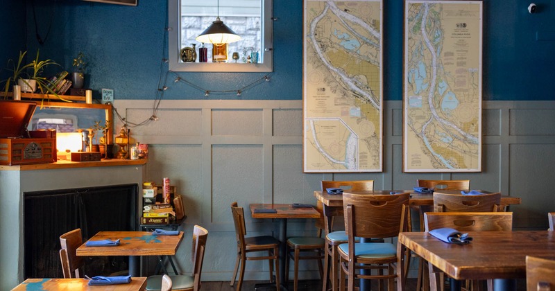 Interior, dining area, fireplace in the corner of the room, framed maps as decoration