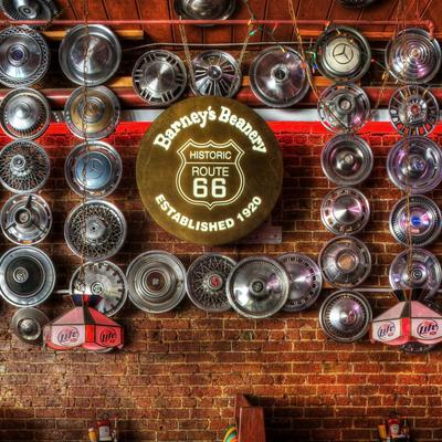 Sign for Historic Route 66 and a brick wall decorated with various vintage hubcaps