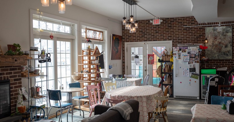 Interior of a café with eclectic furniture, large windows, and pendant lights