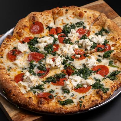 White Pepperoni Pizza topped with spinach and chicken bites.