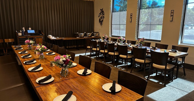 A room set for banquet dining, long tables with place setting and floral display