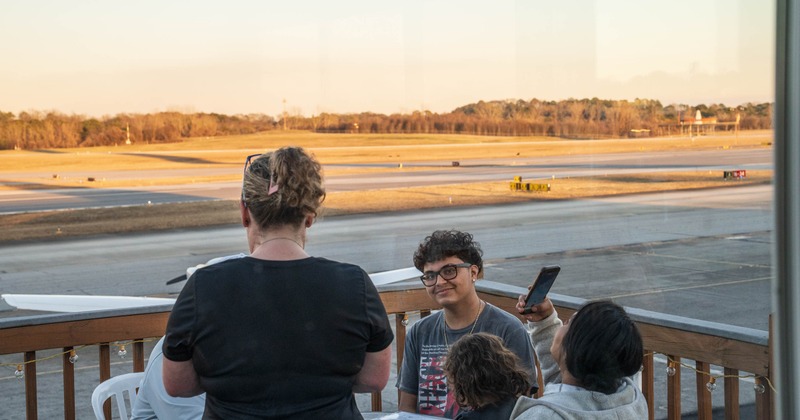 People seated on a deck overlooking runway