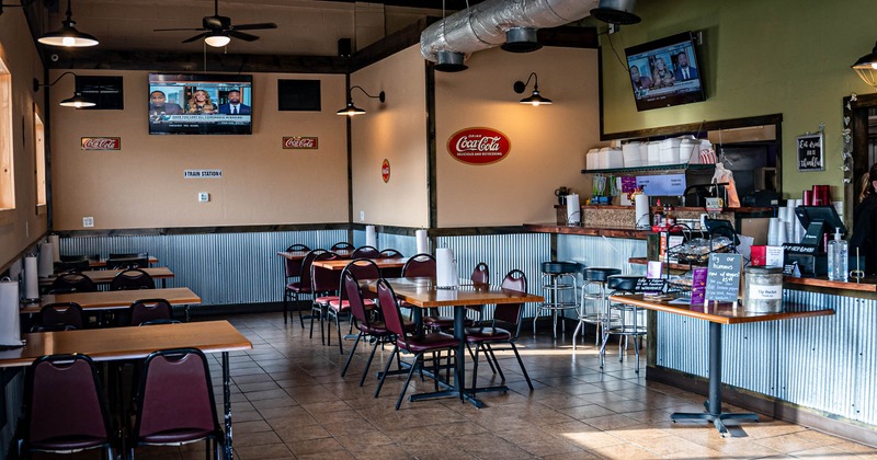 Interior, dining area, tables for four, checkout counter and kitchen on the right