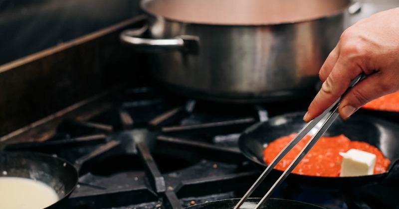 Staff member preparing sauce on stove