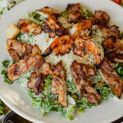 Caesar salad topped with shrimp and chicken.