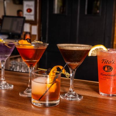 Various colorful cocktails on a wooden counter.