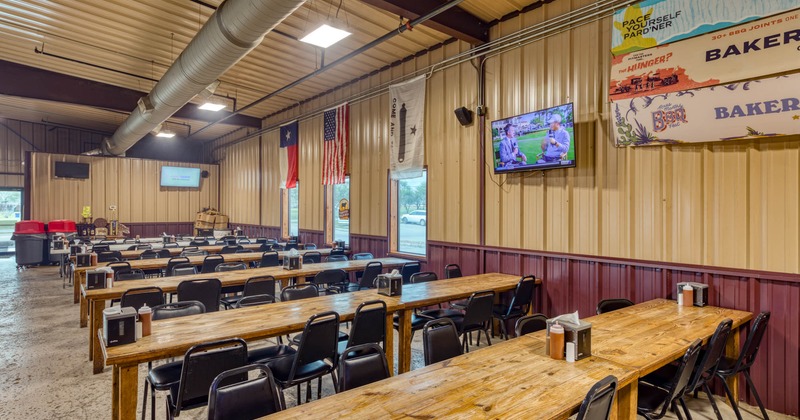 Interior, long tables and chairs ready for guests, tv screen on the wall