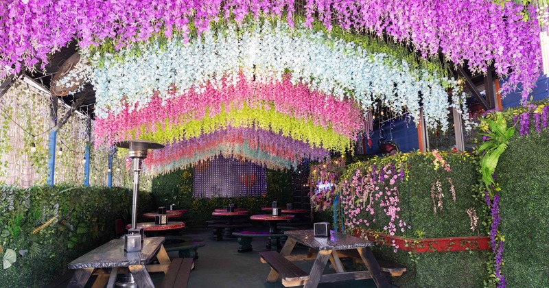 Covered seating area with picnic tables, colorful floral decoration on the ceiling